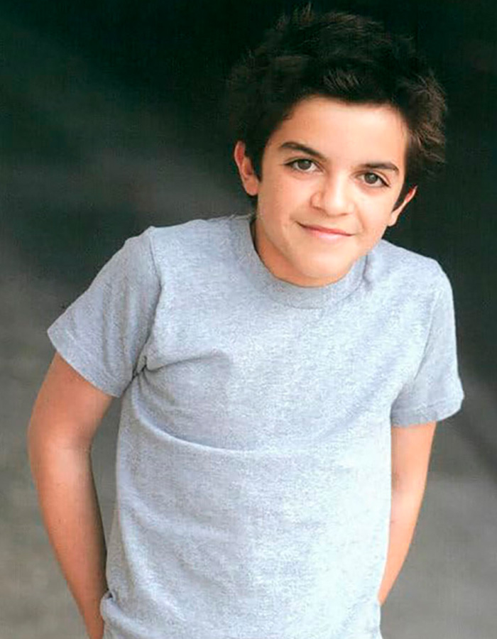Young former child actor Tylor Chase in a gray t-shirt posing with a slight smile against a dark background.