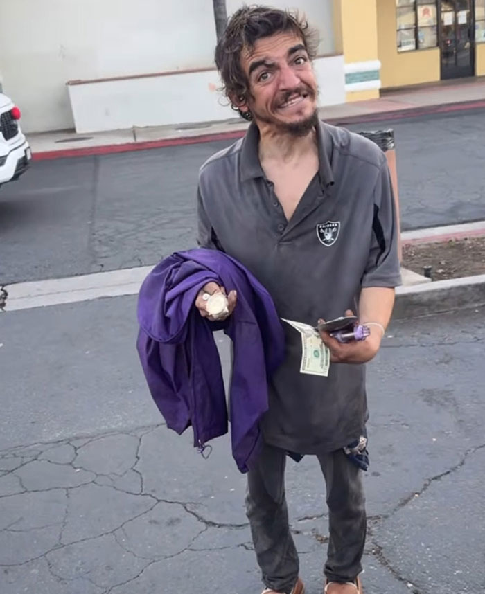 Man holding a purple jacket and cash on a c*****d street, related to Tylor Chase&rsquo;s hospitalization aftermath and friend&rsquo;s revelation.