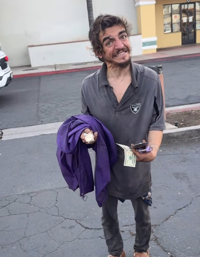 Former child actor Tylor Chase standing on c*****d pavement holding cash and a purple jacket, showing signs of recent troubles.