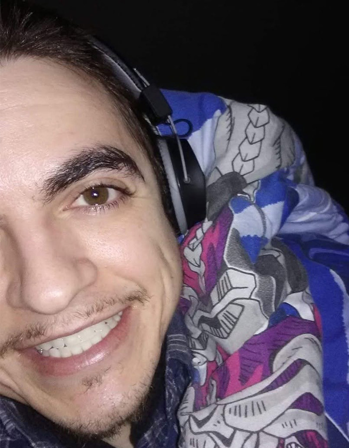 Close-up of former child actor Tylor Chase smiling with headphones and colorful blanket, hinting at recent troubles.