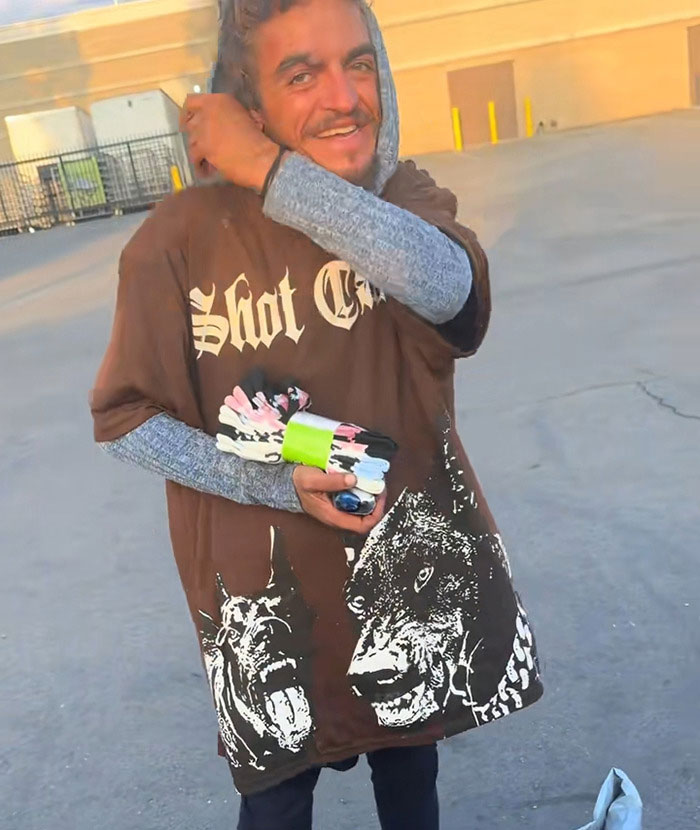 Man wearing a graphic t-shirt outdoors, holding colorful gloves, highlighting Tylor Chase&rsquo;s co-star and homelessness issue.