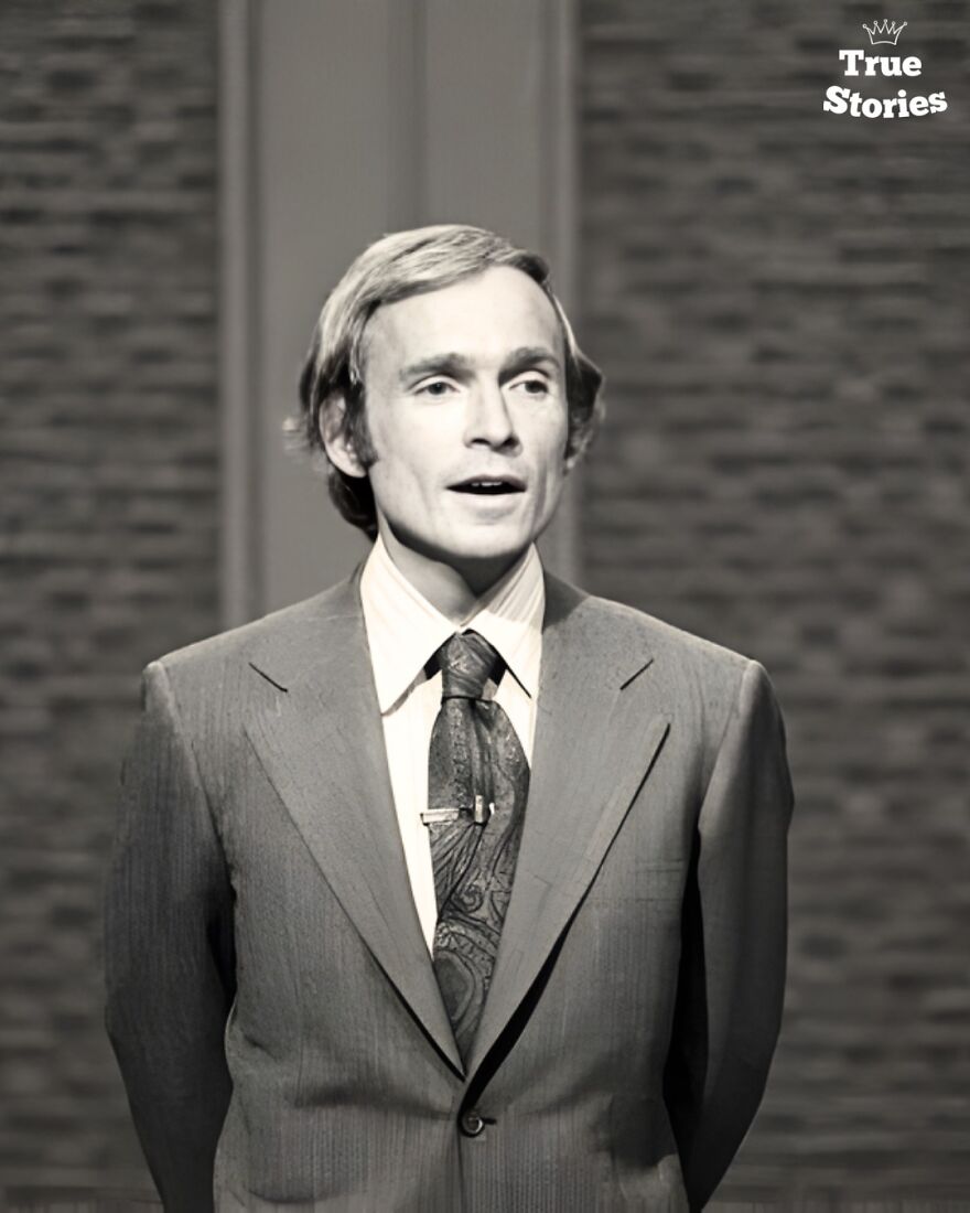 Black and white photo of an important American personality wearing a suit and speaking in a formal setting.