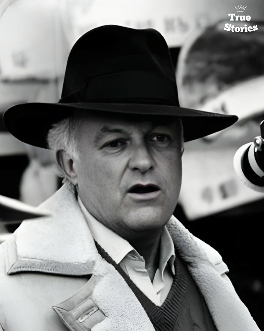 Portrait of an important American personality wearing a black hat and coat in a candid moment outdoors.