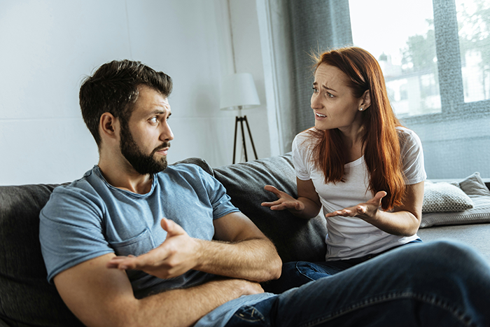 Couple having a tense conversation on a couch, illustrating a stay-at-home mom feeling poor despite receiving monthly fun money.