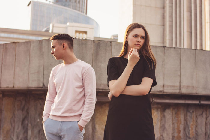 Young couple standing apart looking upset, illustrating tension in a boyfriend girlfriend spending and Hawaii trip conflict.