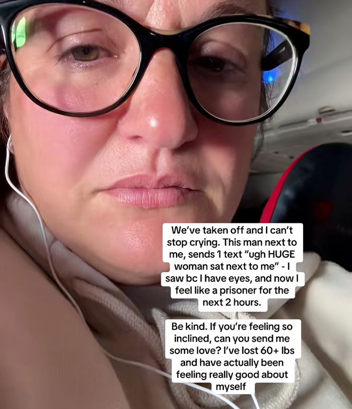 Close-up of woman wearing glasses on flight, visibly upset after catching seatmate&rsquo;s body-shaming text message.