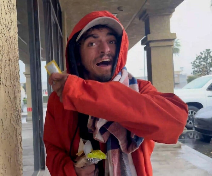 Man in red hoodie and scarf outdoors, holding snacks, linked to Tylor Chase&rsquo;s hospitalization and friend&rsquo;s revelation.