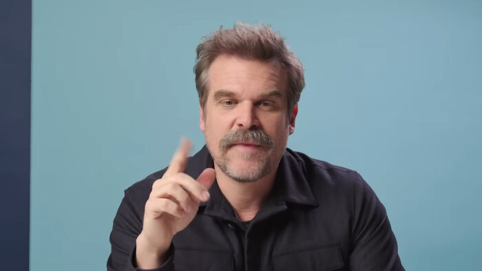 Man with mustache and beard speaking and gesturing, discussing people think celebrities closet skeletons on a blue background.