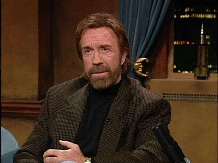 Actor with beard and brown jacket sharing fascinating secrets about celebrities in an intimate interview setting.