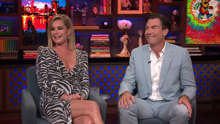 Two celebrities smiling and chatting on a colorful talk show set, sharing fascinating secrets from insiders.