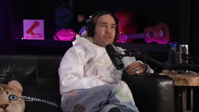 Person in a white hoodie with headphones discussing topics about people thinking celebrities have closet skeletons on a podcast.