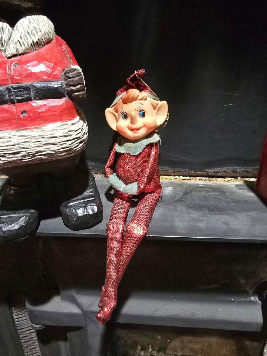 Vintage Christmas decorations featuring a smiling elf doll in red glitter outfit sitting beside a Santa figure.