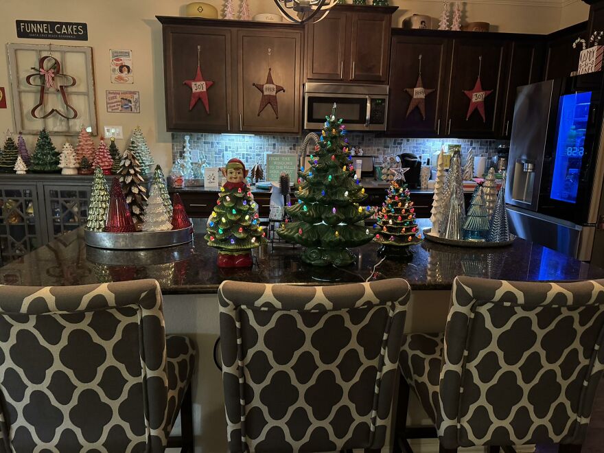 Vintage Christmas decorations including lighted ceramic trees and festive ornaments displayed on a kitchen island countertop.