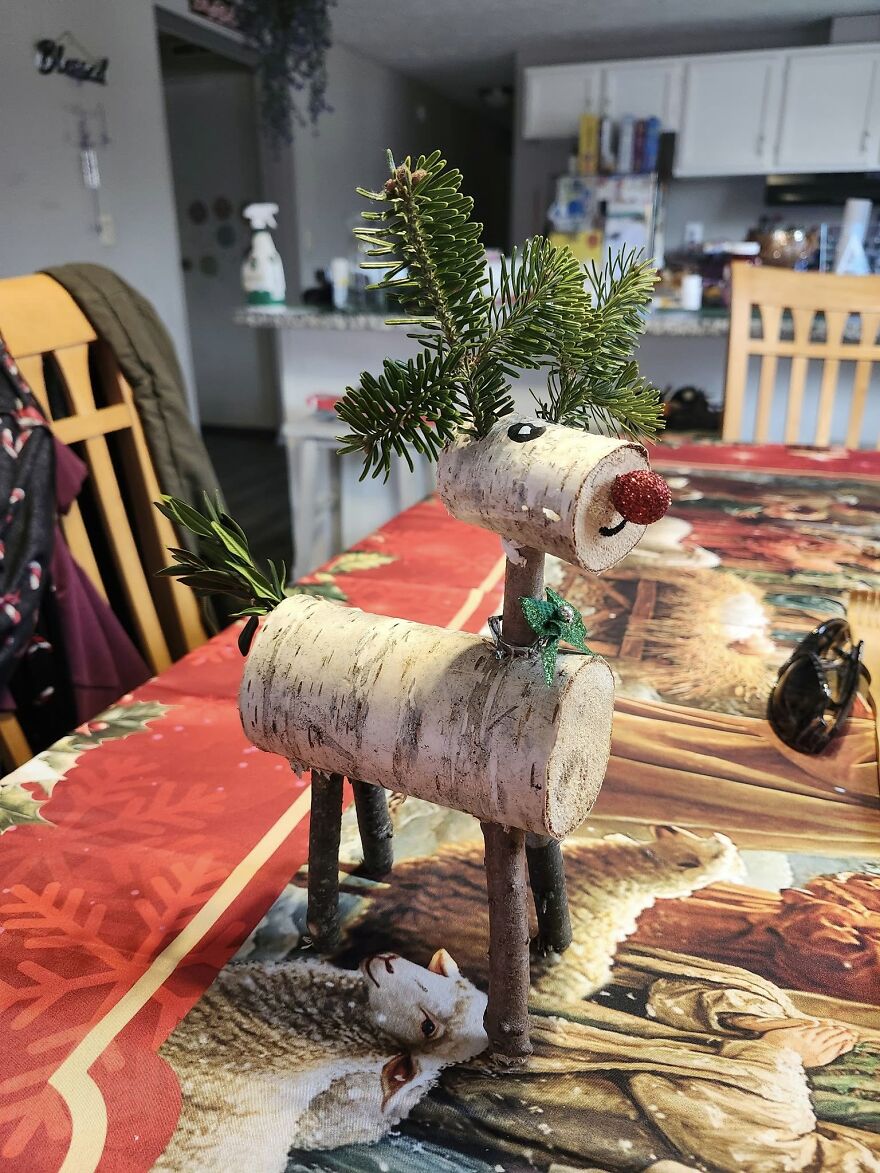 Handcrafted vintage Christmas decoration of a reindeer made from wood and evergreen branches on a festive table.