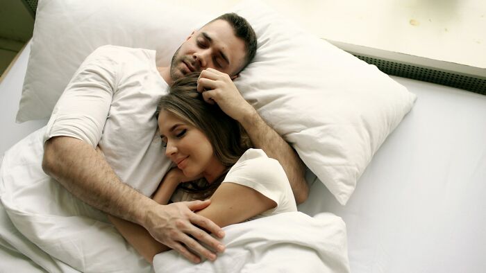 Couple lying in bed embracing peacefully, reflecting on trust and regret in backstabbing relationships.