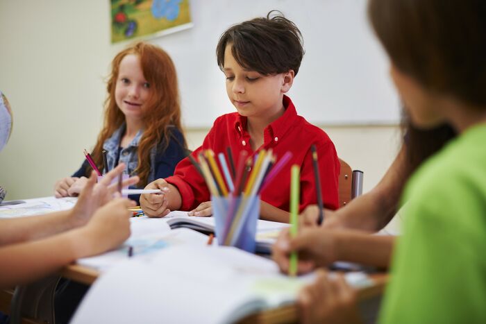 Children focused on creative learning activities at a classroom table demonstrating incredible minds without needing a degree.