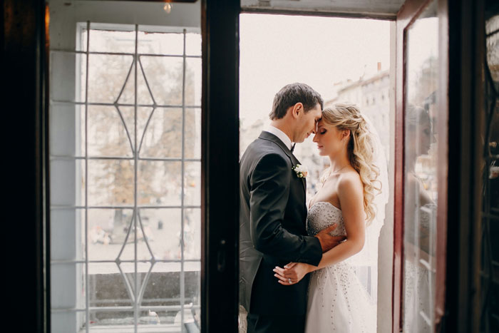Bride and groom embracing tenderly on wedding night, unaware of uninvited guest treating it like a sleepover.