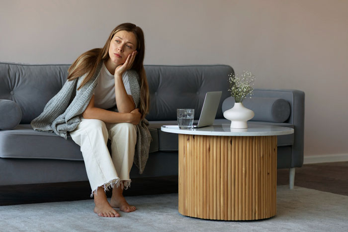 Woman on a couch looking shocked and contemplative after being asked to be the wedding photographer for free.