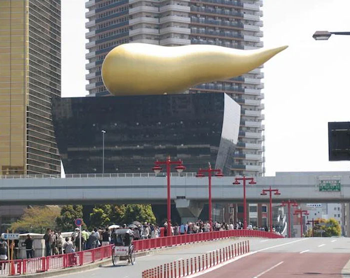 Unique bread-shaped bread factory building with a large golden sculpture on top in an urban cityscape background.