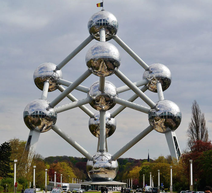 Reflective metal spheres connected by tubes forming a futuristic structure in a park, representing a unique bread-shaped bread factory design.
