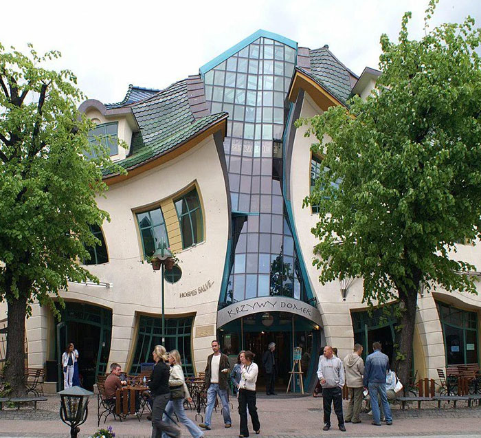 Crooked building with curved windows and roof, an example of bread-shaped bread factory architecture in a busy urban area.