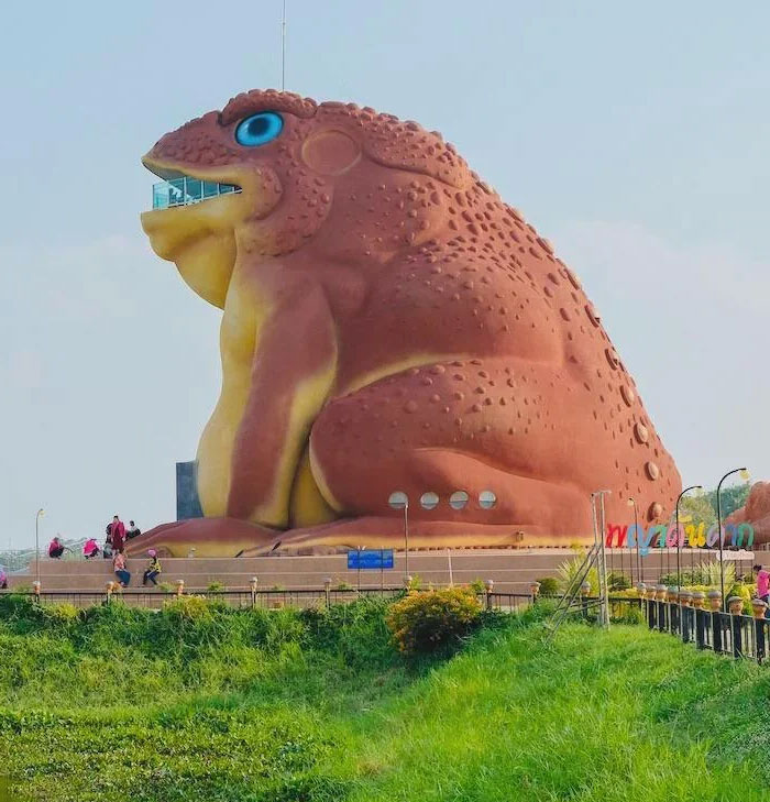 Giant frog-shaped building with unique design, standing near greenery and people, showcasing one of the weirdest buildings worldwide.