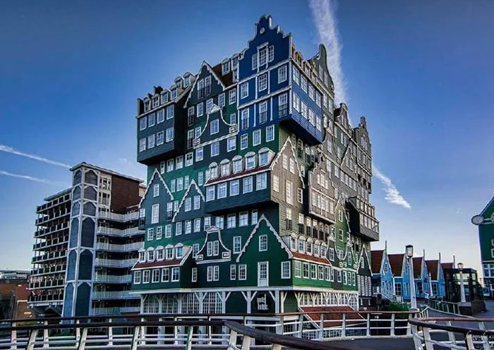 Unique bread-shaped bread factory building with layered design and green facade under a clear blue sky.