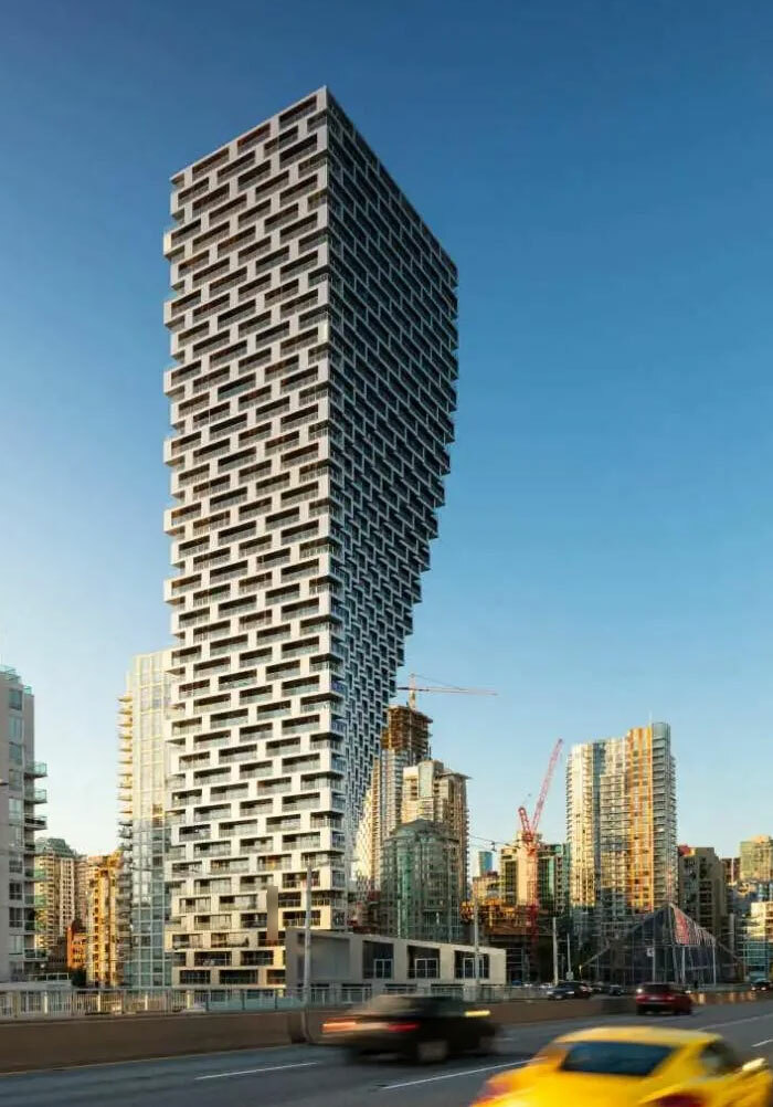 Modern bread-shaped bread factory building with unique stepped architecture set against a clear blue sky in an urban area.