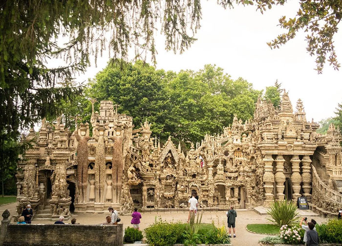 Intricately designed bread-shaped bread factory building surrounded by greenery and visitors taking photos.