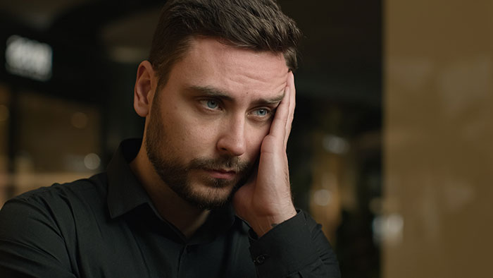 Young man with beard looking worried, reflecting on surprising DNA tests revealing shocking family relationships.
