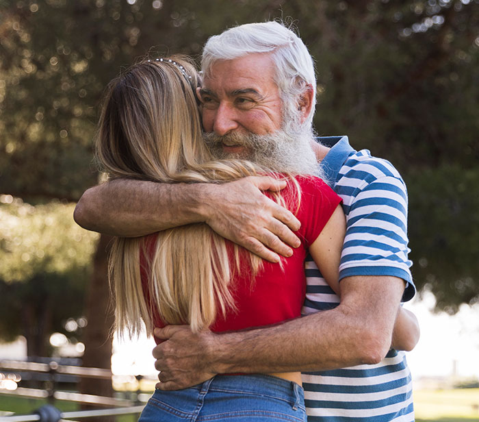 Older man and young woman hugging outdoors, illustrating DNA tests revealing surprising family relationships.