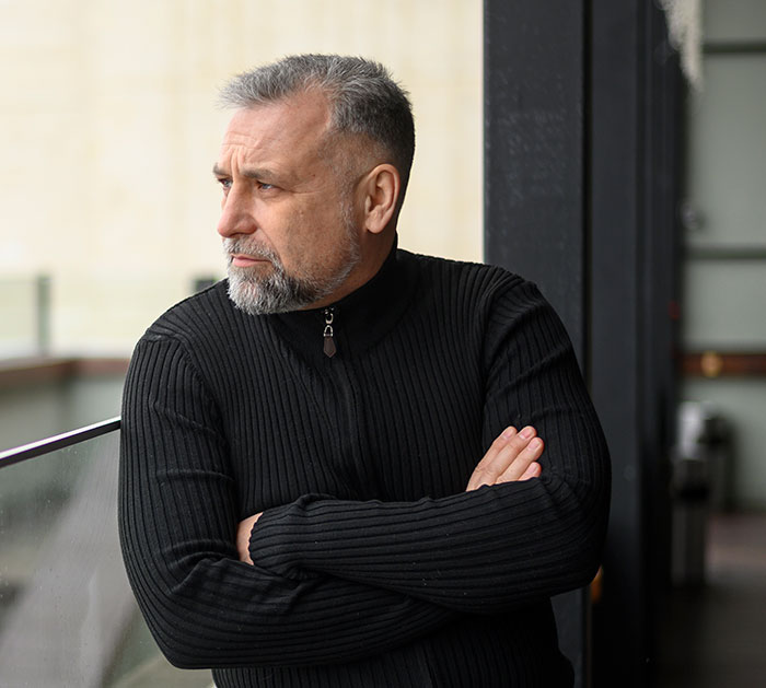 Middle-aged man in black sweater looking away thoughtfully, illustrating DNA tests revealing surprising family relationships.