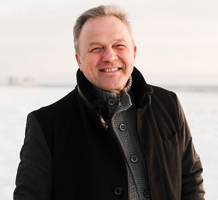 Middle-aged man smiling outdoors in winter, representing DNA tests revealing interesting and shocking family information.