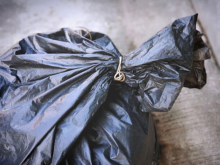 Black garbage bag tied with a string, representing a strange excuse for missing work involving a chinchilla and a wallet.