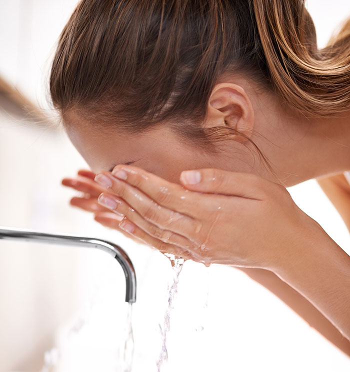 Woman washing her face at a sink, representing one of the strange excuses for missing work like chinchilla ate her wallet.