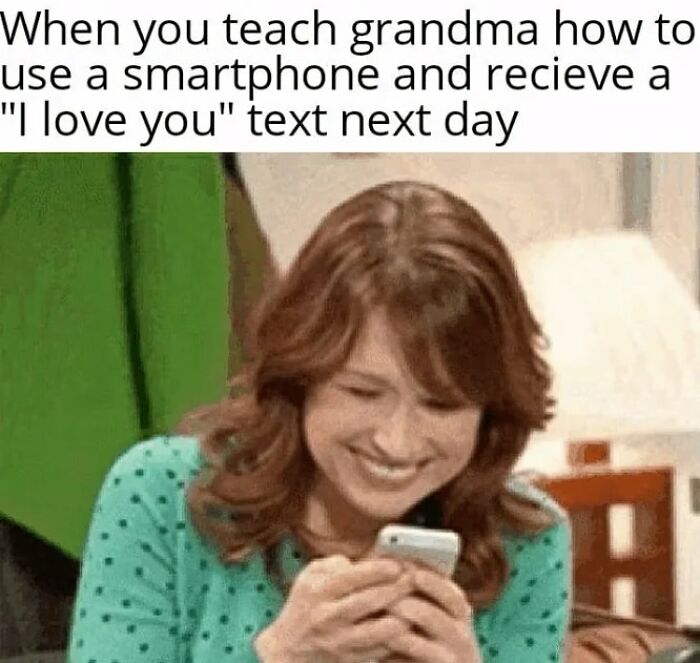Woman smiling warmly at her smartphone after teaching grandma to use it, capturing a sweet wholesome moment.