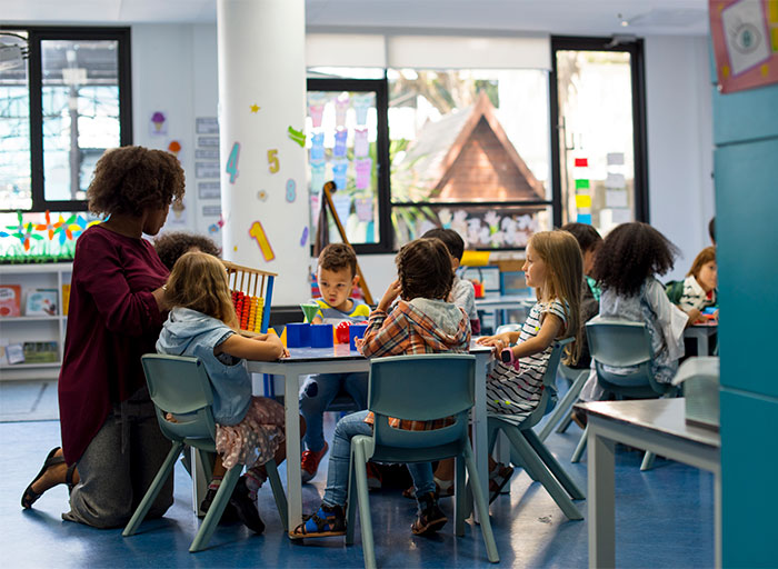 Daycare classroom with children and teacher engaging in activities, highlighting SAHM and mom parenting choices. Daycare classroom with children and teacher engaging in activities, highlighting SAHM and mom parenting choices.