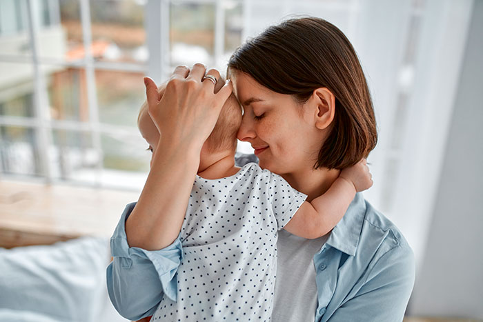 Mother gently embracing her baby indoors, illustrating the emotional bond and challenges faced by stay-at-home moms. Mother gently embracing her baby indoors, illustrating the emotional bond and challenges faced by stay-at-home moms.