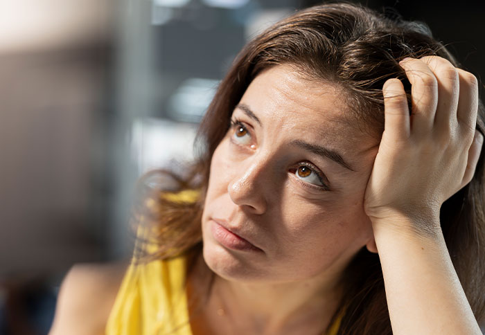 Sad woman reflecting on divorce regret, holding her head with a pensive expression, facing a reality check.