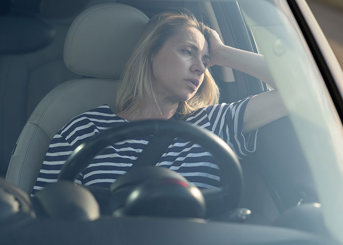 Tired mom sitting in car, looking stressed and overwhelmed after running away from her kids on Christmas day.