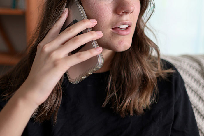 Young woman in black shirt talking on phone, reacting to toxic man venting about traditional wives and logic flaws.