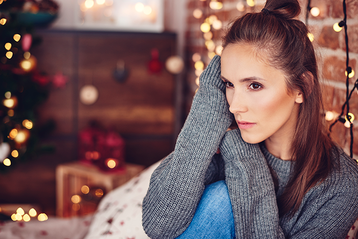 Woman looking horrified indoors near festive Christmas decor after receiving HOA fines for decorations deemed too festive Woman looking horrified indoors near festive Christmas decor after receiving HOA fines for decorations deemed too festive