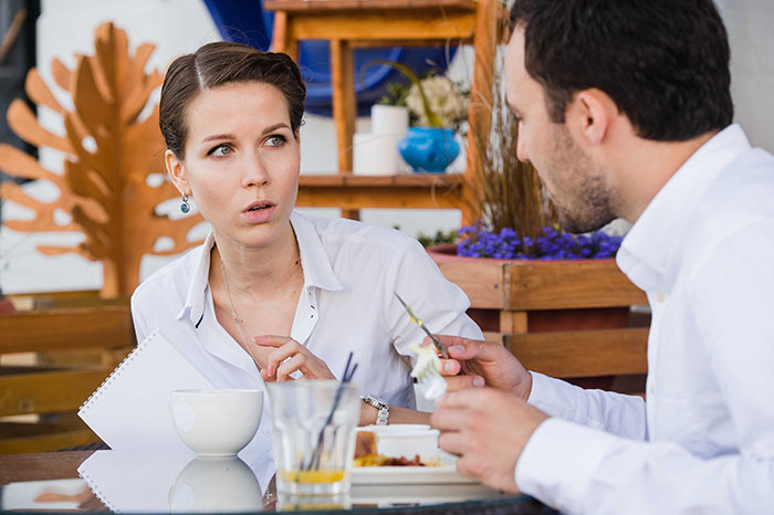Woman at a table not giving in to social pressure from coworkers, showing confidence despite awkward feelings. Woman at a table not giving in to social pressure from coworkers, showing confidence despite awkward feelings.