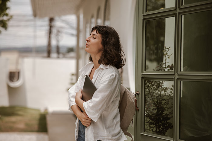 Woman standing outside with a laptop, showing confidence and not giving in to social pressure from coworkers. Woman standing outside with a laptop, showing confidence and not giving in to social pressure from coworkers.