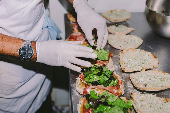 Person wearing gloves preparing sandwiches with fresh lettuce and meat, illustrating a brand mistake that annoyed customers.