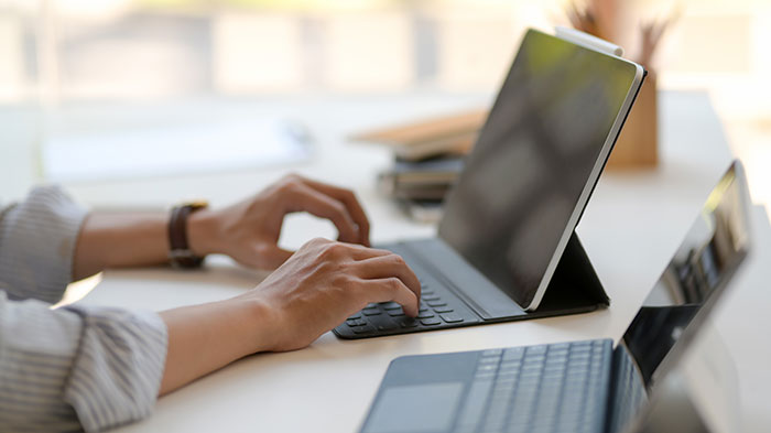 Person typing on a tablet keyboard at a bright desk, illustrating brands making mistakes that annoyed customers.