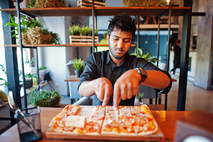 Man slicing a pizza in a modern restaurant illustrating brand mistakes that annoyed people leading to boycotts.