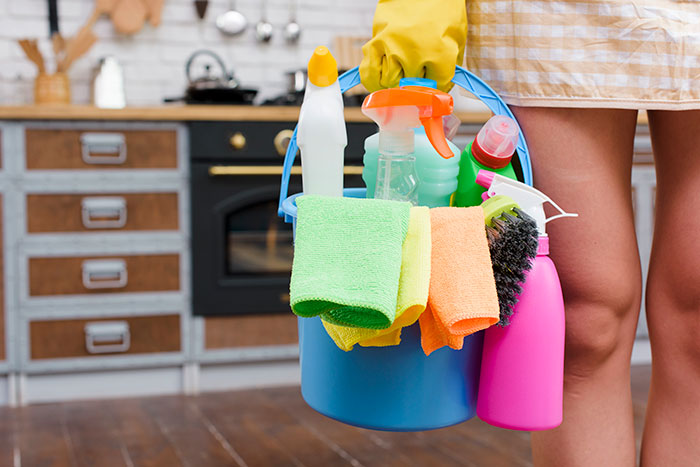 Person holding cleaning supplies and cloths in a kitchen setting, illustrating worst gifts received story concept.