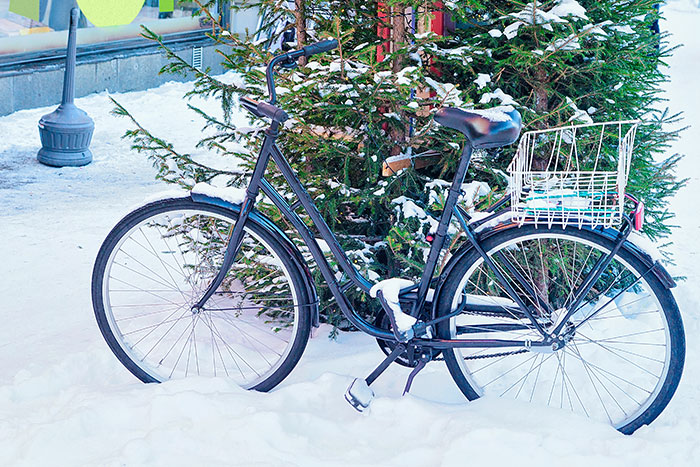 Black bicycle parked in snowy street near Christmas trees, illustrating the worst gifts people have ever received.