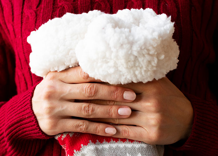 Hands holding a cozy white fluffy slipper as an example of an insensitive and tasteless gift like a gym membership.